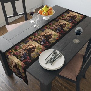Könnte beinhalten: Ein schwarzer und brauner Tischläufer mit einem Blumendesign und einem sich wiederholenden Bild eines braunen und weißen Hundes. Der Läufer liegt auf einem dunklen Holztisch mit einem weißen Teller und Besteck.