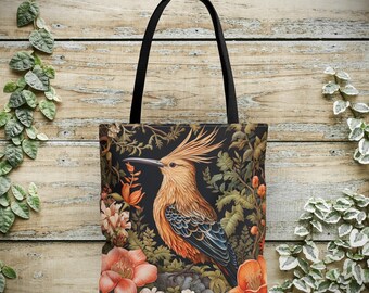 Könnte beinhalten: Eine schwarze Tragetasche mit einem bunten Vogel- und Blumendesign. Der Vogel ist orange, blau und braun mit einem langen, spitzen Schnabel. Die Blumen sind rosa, weiß und grün. Die Tasche hat schwarze Henkel.