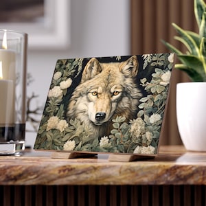 May include: A close-up of a wolf's face peering through a thicket of white flowers and green leaves. The wolf has a light brown coat and piercing yellow eyes.