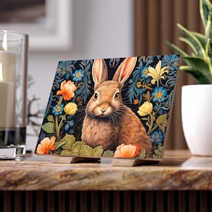 Pode incluir: Um coelho castanho com orelhas compridas senta-se num campo de flores. O coelho tem uma mancha branca no peito e olha diretamente para o observador. As flores são de várias cores, incluindo amarelo, laranja, azul e branco. O fundo é azul escuro.