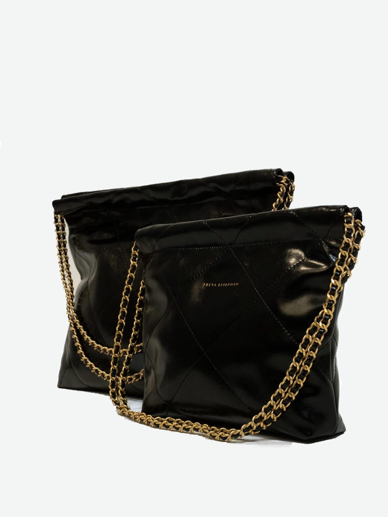 Puede incluir: Dos bolsos negros acolchados con correas de cadena doradas. Los bolsos tienen un acabado brillante y un patr&oacute;n de diamantes. El nombre de la marca "FREYA ESTHERMAN" est&aacute; impreso en dorado en la parte delantera de un bolso.