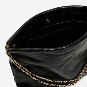 Puede incluir: Bolso de mano de cuero negro acolchado con cadena dorada. El bolso tiene un cierre de solapa con un broche magn&eacute;tico y un bolsillo interior. Un dise&ntilde;o cl&aacute;sico, adecuado para el uso diario.