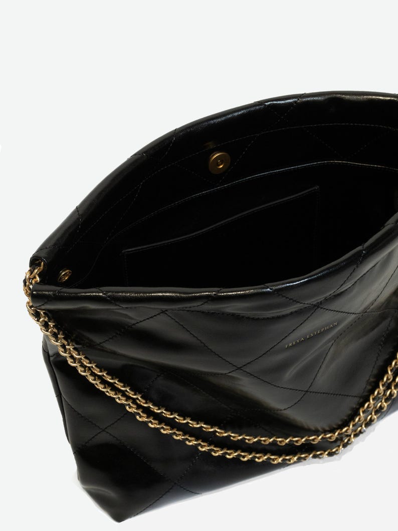 Puede incluir: Bolso de mano de cuero negro acolchado con cadena dorada. El bolso tiene un cierre de solapa con un broche magn&eacute;tico y un bolsillo interior. Un dise&ntilde;o cl&aacute;sico, adecuado para el uso diario.