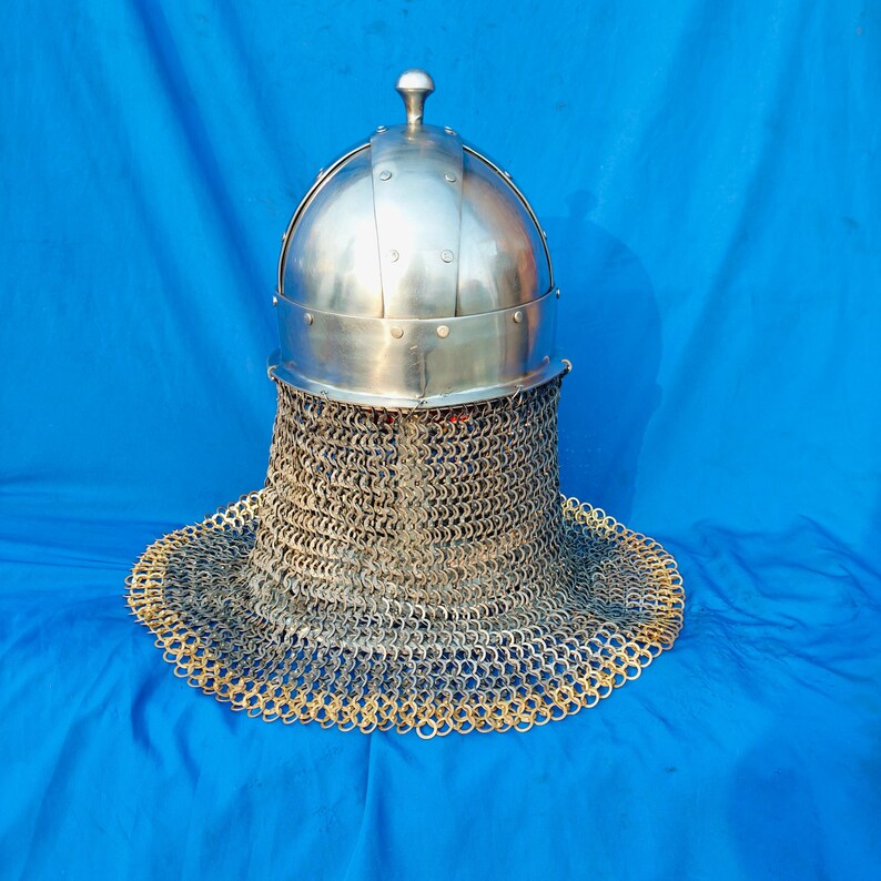 May include: A silver helmet with a chainmail coif. The helmet has a rounded top and a pointed tip. The chainmail coif is made of small metal rings linked together.