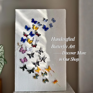 May include: Handcrafted butterfly art on a white canvas. The artwork features a collection of colorful butterflies in shades of blue, yellow, red, pink, and black. Text on the canvas reads "Handcrafted Butterfly Art - Discover More in Our Shop."