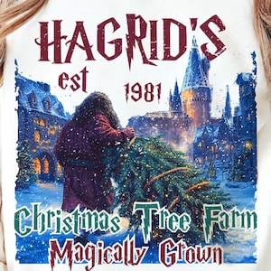 May include: White sweatshirt with a graphic featuring Hagrid, a Christmas tree, and Hogwarts Castle. The text reads "Hagrid's est 1981 Christmas Tree Farm Magically Grown" in a burgundy and green color scheme.