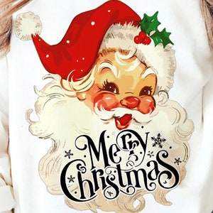 May include: White sweatshirt featuring a vintage Santa Claus graphic with a red hat, rosy cheeks, and a fluffy white beard. The words "Merry Christmas" are written in a decorative font below the Santa illustration. A festive holiday apparel item.