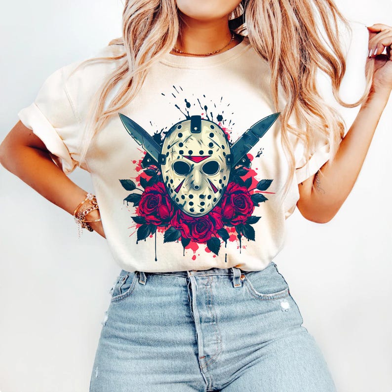 Peut inclure: T-shirt cr&egrave;me avec un motif graphique. Le motif comprend un masque de hockey avec deux couteaux crois&eacute;s, entour&eacute; de roses rouges et d'&eacute;claboussures de peinture. Le th&egrave;me g&eacute;n&eacute;ral est l'horreur.