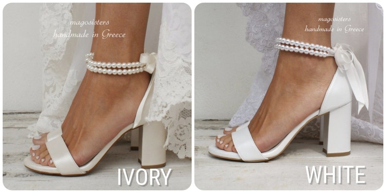 Puede incluir: Dos pares de tacones de novia blancos con correas de tobillo de perlas y lazos de sat&eacute;n. Los tacones est&aacute;n disponibles en marfil y blanco.