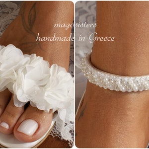 May include: White bridal sandals with a flower embellishment on the toe and a beaded ankle strap. The sandals are handmade in Greece.