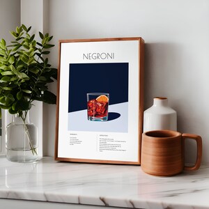 May include: A framed poster with a minimalist design featuring a glass of Negroni cocktail with an orange slice. The poster includes the ingredients and instructions for making the drink.