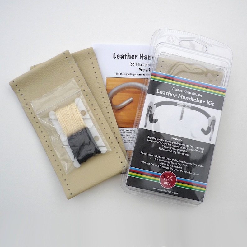 May include: A vintage road racing leather handlebar kit with two cream-colored leather covers, cream and black thread, and instructions. The kit is packaged in a clear plastic box with a colorful logo and the text "Vintage Road Racing Leather Handlebar Kit".