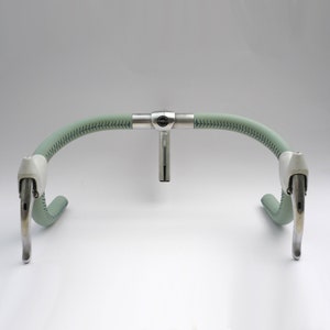 Pu&ograve; includere: Una coppia di leve freno per bicicletta argentate fissate a un manubrio rivestito in pelle verde con uno stelo argentato e un logo "Cinelli".