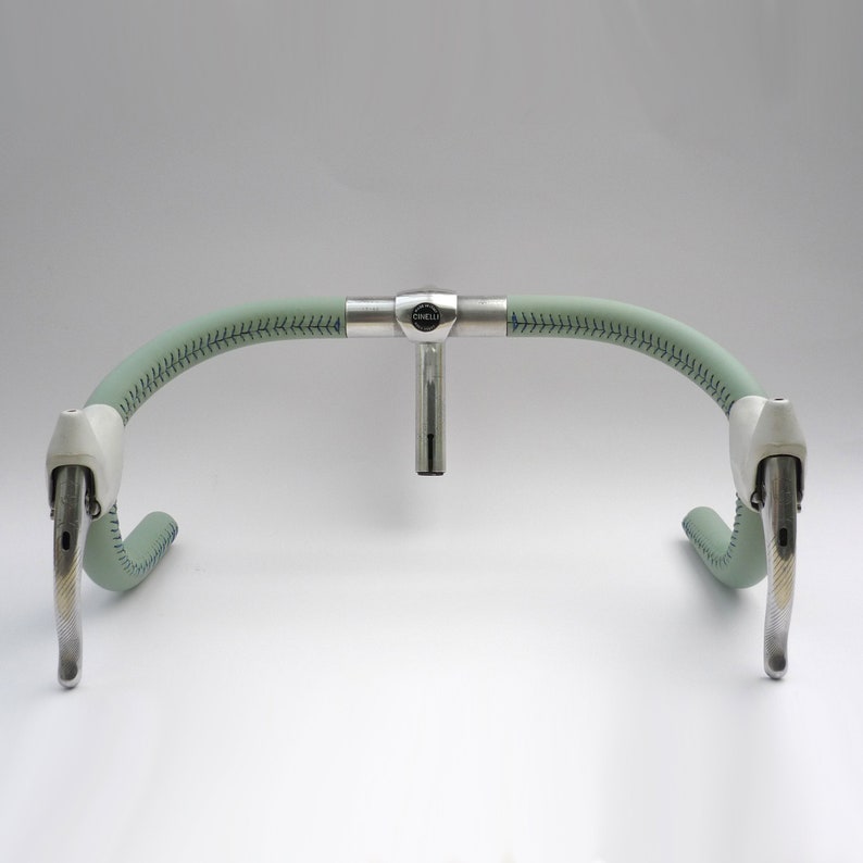 Pu&ograve; includere: Una coppia di leve freno per bicicletta argentate fissate a un manubrio rivestito in pelle verde con uno stelo argentato e un logo "Cinelli".