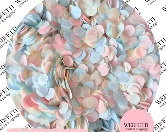 May include: A collection of small, circular paper confetti pieces in soft pastel shades of light pink, baby blue, and cream. The confetti is densely packed together, creating a textured surface of overlapping matte paper circles in various light colors.