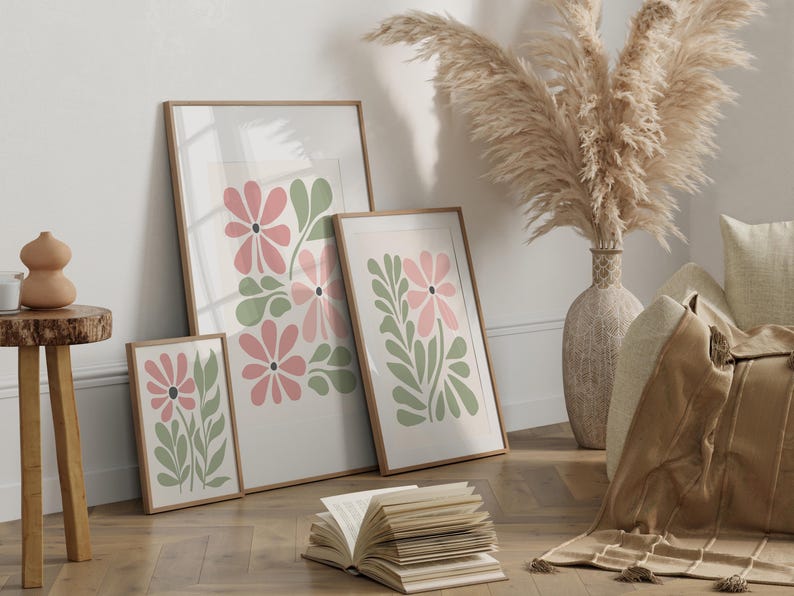 May include: Three framed prints with a floral design. The prints feature pink and green stylized flowers on a white background. The frames are all brown wood.