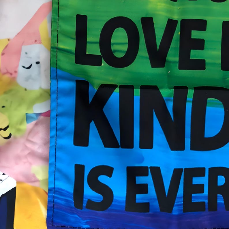 May include: A rainbow-colored fabric banner with the text "Love is Kind is Ever" in black lettering.