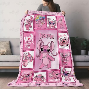 Op de afbeelding: Een roze fleece deken met een collage van Angel uit Lilo en Stitch in verschillende poses. In het midden staat het woord Name in grote letters. Andere teksten zijn Ohana Means Family, Angel Experiment 624, Hello en I'm Not Weird.