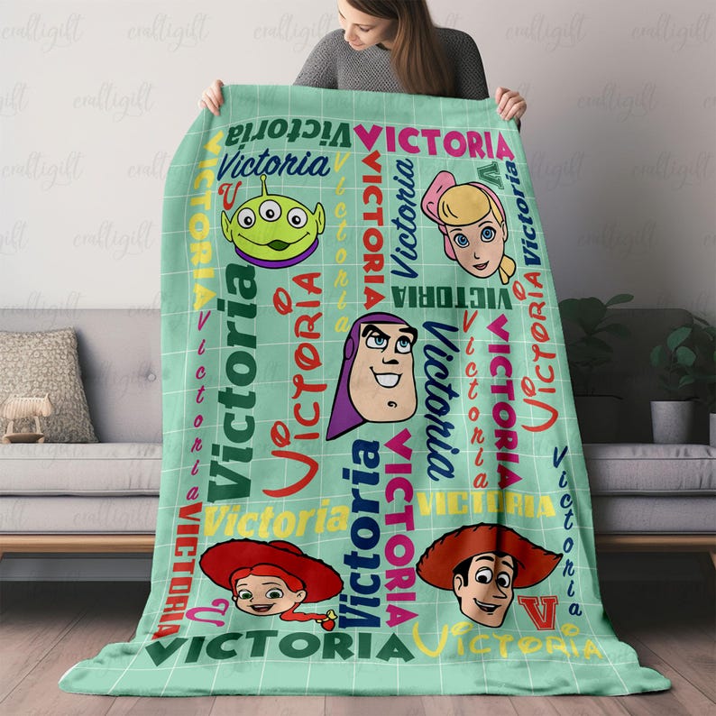 以下が含まれることがあります： 白のグリッドパターンと様々な色やフォントでVictoriaという名前がプリントされたライトグリーンのスローブランケット。ブランケットには、エイリアン、ブロンドの人形、スペースレンジャー、カウガール、カウボーイなどの漫画キャラクターの頭部が描かれています。