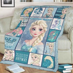 May include: A light blue and white fleece blanket featuring a collage of Elsa from Frozen, including a large central portrait, various smaller character illustrations, snowflake patterns, and text such as "The cold never bothered me anyway."