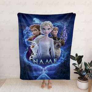 Op de afbeelding: Een donkerblauwe fleece deken met personages uit de animatiefilm "Frozen". Het ontwerp bevat Elsa, Anna, Kristoff, Olaf en Sven, omringd door een blauwe gloed. Het woord "NAME" is prominent weergegeven.