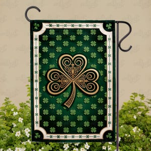 Può includere: Una bandiera da giardino verde con un design a trifoglio dorato. La bandiera ha uno sfondo verde scuro con trifogli più piccoli e un bordo bianco con un motivo decorativo. Il trifoglio è il punto focale.