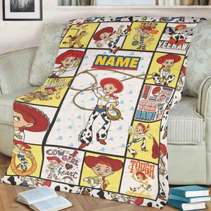 May include: A fleece blanket featuring a grid pattern with multiple illustrations of the character Jessie from Toy Story. The design includes yellow and white panels with text such as NAME, YEEHAW, and TOUGH COOKIE, alongside images of Jessie with a lasso.