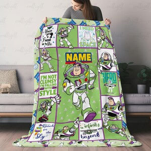 K&ouml;nnte beinhalten: Eine gr&uuml;ne Fleecedecke mit mehreren Feldern, die Buzz Lightyear aus Toy Story zeigen. Das Design enth&auml;lt die Texte "You've got a friend in me", "I need space", "I'm not clumsy I'm falling with style", "Reach for the sky" und "To infinity and beyond".