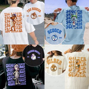 May include: Collection of graphic t-shirts featuring cartoon dog characters. Designs include "Tag Barker," "Scooch," "Cheddar Biscuit," and "Gilber," each with a unique illustration and the year "2021." Shirts come in various colors.