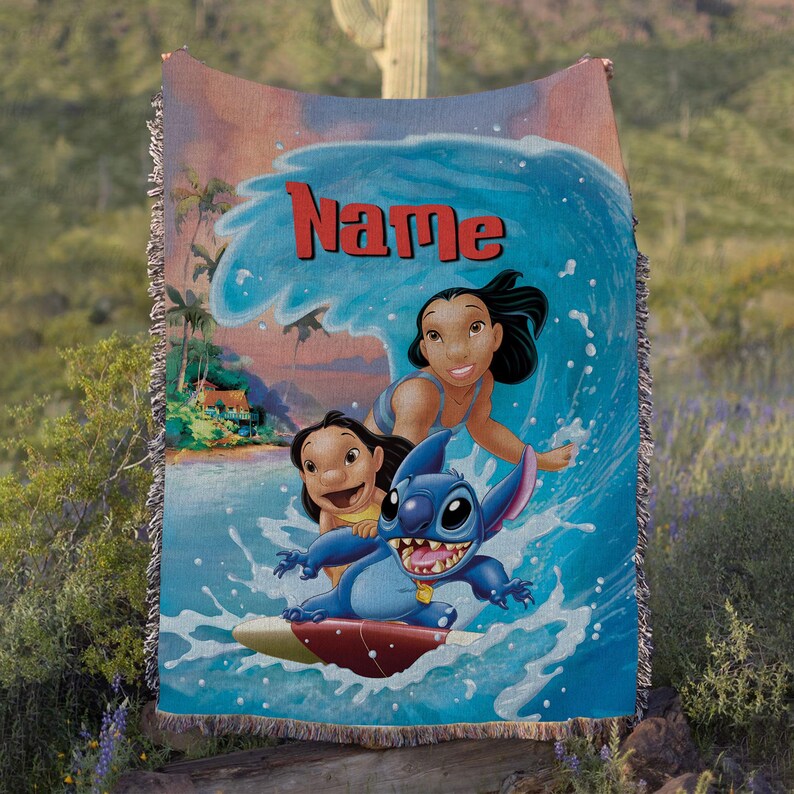 Puede incluir: Una manta tejida con una vibrante ilustraci&oacute;n de Stitch surfeando una ola con dos chicas. La manta tiene una escena oce&aacute;nica azul y blanca con el nombre "Name" en letras rojas. La manta tiene un borde con flecos.