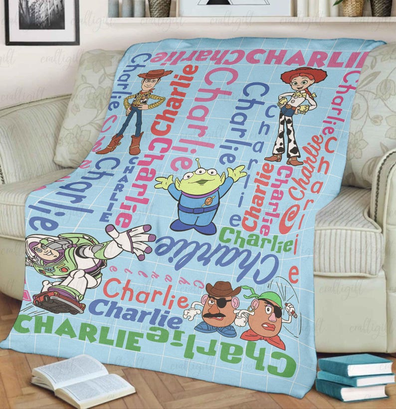 May include: A light blue fleece blanket featuring a grid pattern and the repeated name Charlie in various colors. The blanket displays Toy Story characters including Woody, Jessie, Buzz Lightyear, an Alien, and two Potato Head figures.