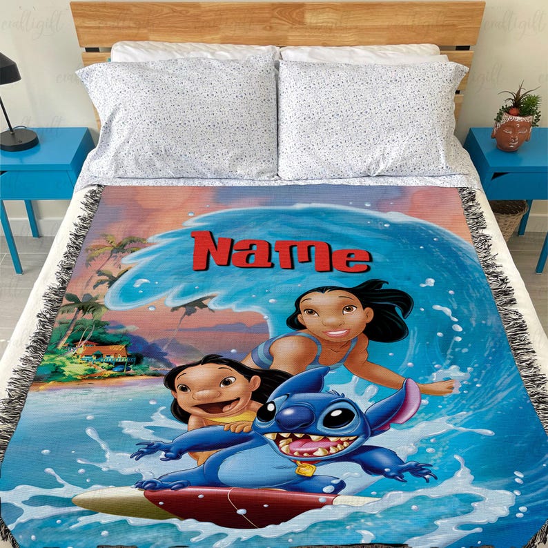 Puede incluir: Una manta tejida con una vibrante ilustraci&oacute;n de personajes surfeando una ola. El dise&ntilde;o incluye la palabra "Name" en rojo, con una escena oce&aacute;nica azul y blanca. La manta tiene un fleco negro.