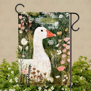 May include: A garden flag featuring a white goose with an orange beak, set amidst a lush garden scene with pink and white flowers. The artwork has a painterly style, with a pond in the background.