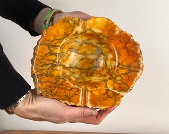 May include: A large, orange and white marble ashtray with a rough, textured surface.
