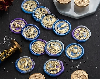 Op de afbeelding: Een verzameling van twaalf blauwe en gouden waszegels met dierenriemsymbolen. De zegels zijn gerangschikt op een zwart oppervlak.