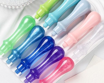 May include: Assortment of colorful wax seal stamp handles. The handles are made of plastic and have a variety of colors, including green, blue, pink, purple, and white. Some of the handles have glitter.