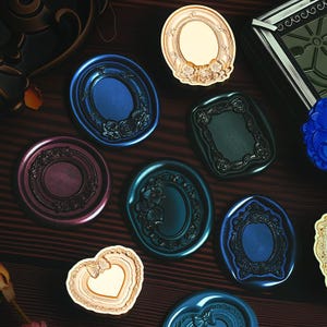 Könnte beinhalten: Eine Sammlung dekorativer Wachssiegel in verschiedenen Farben, darunter Blau, Gold und Burgunderrot. Die Siegel weisen verzierte Rahmen, florale Designs und Herzformen auf. Die Siegel liegen auf einer dunklen Holzoberfläche.