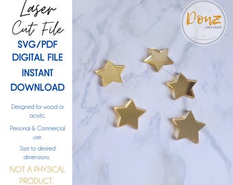 May include: Five gold-colored star-shaped cutouts are scattered on a white and gray marble surface. The image includes text that reads "Laser Cut File," "SVG/PDF DIGITAL FILE INSTANT DOWNLOAD," and "Designed for wood or acrylic."
