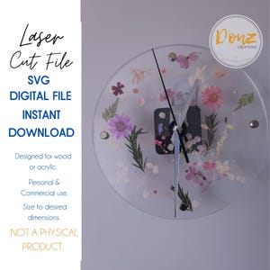 May include: A clear clock face with a silver clock hand and a white background. The clock face is decorated with pressed flowers and leaves. The clock is labeled "Donz Creationz".