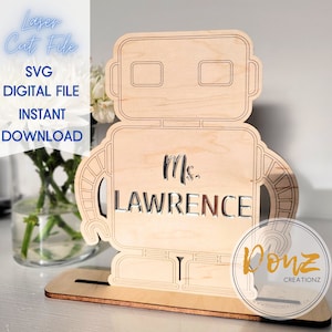 May include: A laser cut wooden robot cutout with a stand. The robot has a nameplate that says "Ms. LAWRENCE".