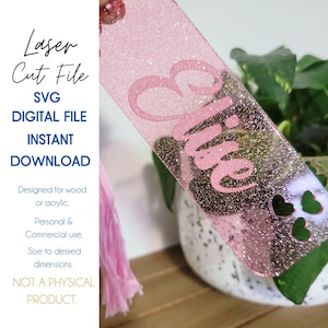 May include: Pink glitter laser cut bookmark with the name "Elise" and three heart cutouts.  The bookmark is designed for wood or acrylic and is available for personal and commercial use.