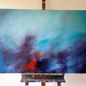 May include: Abstract painting on canvas with a blue, purple, and red color scheme. The painting is on an easel.