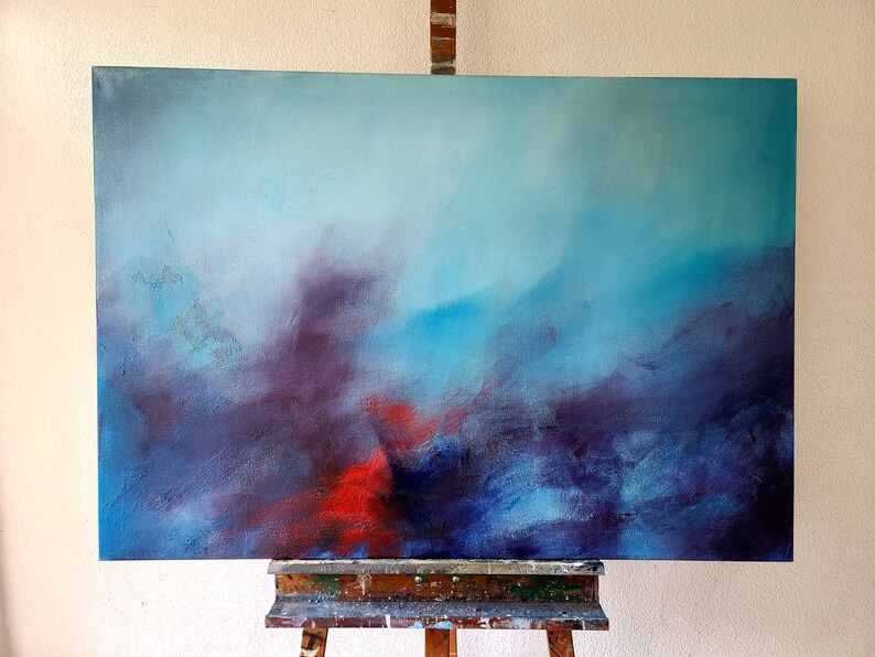May include: Abstract painting on canvas with a blue, purple, and red color scheme. The painting is on an easel.