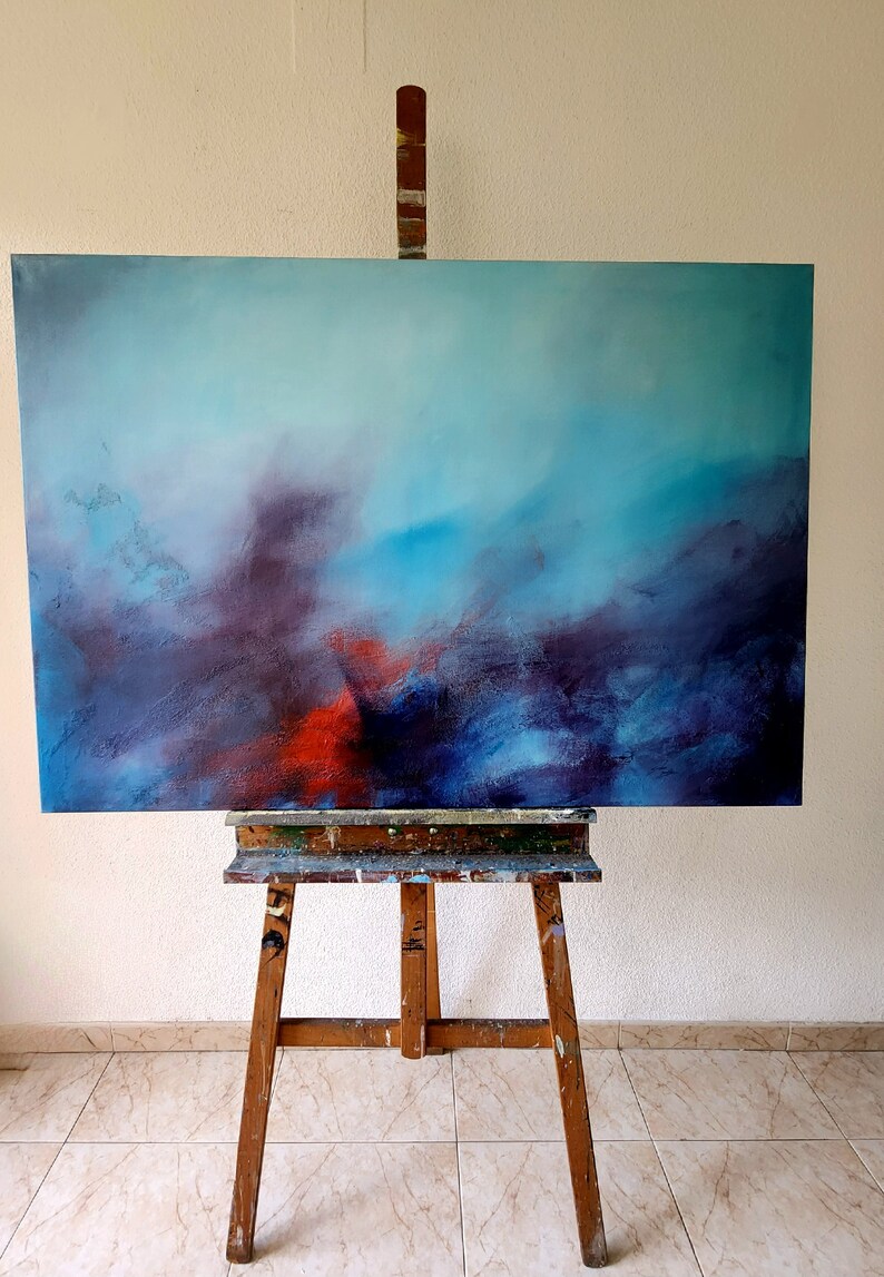 May include: Abstract painting on canvas with shades of blue, purple, and red. The painting is on an easel in a room with tiled floors.