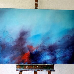 May include: Abstract painting on canvas with a blue, purple, and red color scheme. The painting is on an easel.