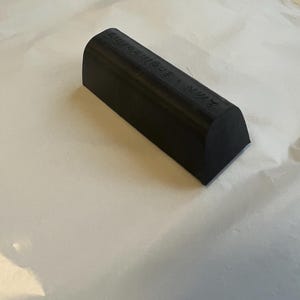 May include: A black, rectangular object with rounded ends. The object has the text "A.M. Engineering" printed on the top surface. The object is resting on a white surface.