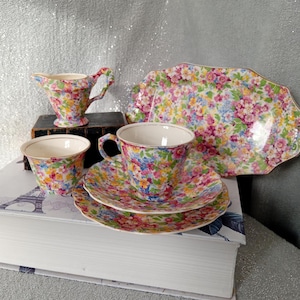 Könnte beinhalten: Ein Vintage-Tee-Set mit Blumenmuster. Das Set enthält eine Teekanne, eine Milchkännchen, eine Zuckerdose, eine Tasse und eine Untertasse sowie ein Serviertablett.