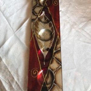 May include: A rectangular glass dish with a red, gold and white geometric design. The dish has three small, round indentations.