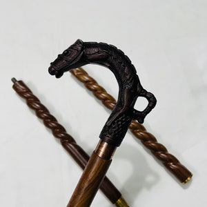 Pu&ograve; includere: Un bastone da passeggio in legno con un manico scolpito a forma di testa di cavallo. Il bastone &egrave; marrone e ha un design intrecciato.