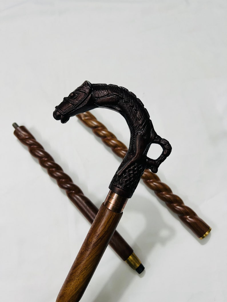 Pu&ograve; includere: Un bastone da passeggio in legno con un manico scolpito a forma di testa di cavallo. Il bastone &egrave; marrone e ha un design intrecciato.